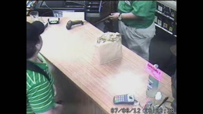Surveillance video shows the suspect display his gun before the cashier adds cash to the man's bag of beer.