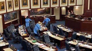 Crews in blue medical gowns swabbed the Florida House floor on March 9, 2020.