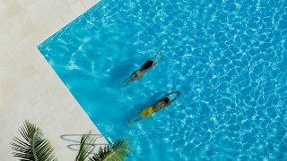 Aerial view of woman and man swimming in a pool - stock photo