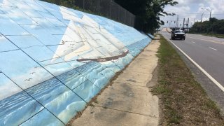 Traffic passes a mural of the last slave ship to the U.S. along Africatown Boulevard