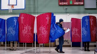 A man walks out of a voting booth during the New Hampshire Primary at Parker-Varney Elementary School, Tuesday, Feb. 11, 2020, in Manchester, N.H.