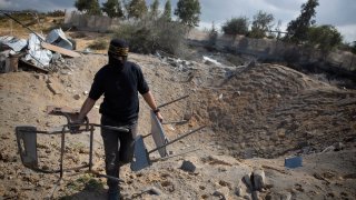 A masked Palestinian militant checks the damage following overnight Israeli airstrikes on an Islamic Jihad military base in the town of Khan Younis, Southern Gaza Strip, Monday, Feb. 24, 2020.