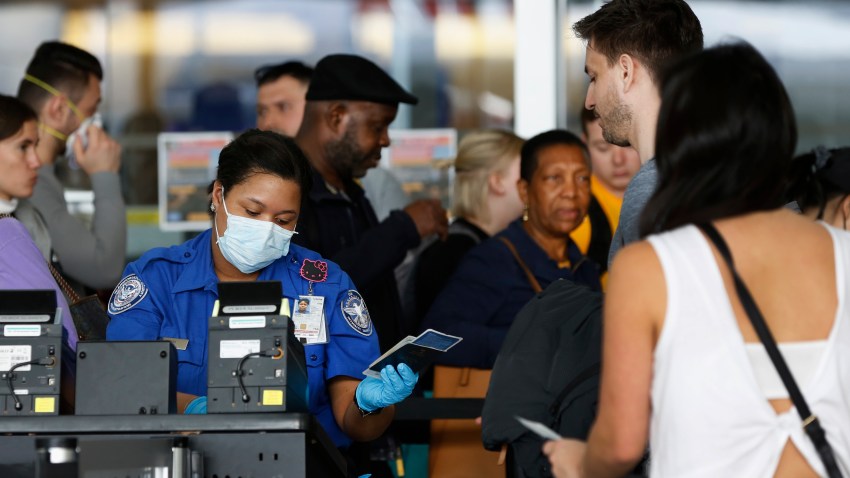 A TSA agent hands a passport back to a traveler as she screens travelers
