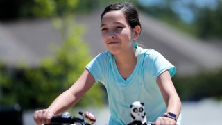 Juliet Daly, 12, rides her bike outside her home in Covington, La.