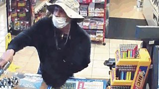 This image from surveillance video shows a man, believed to be William Rosario Lopez wearing a surgical mask, with a gun in a Connecticut convenience store