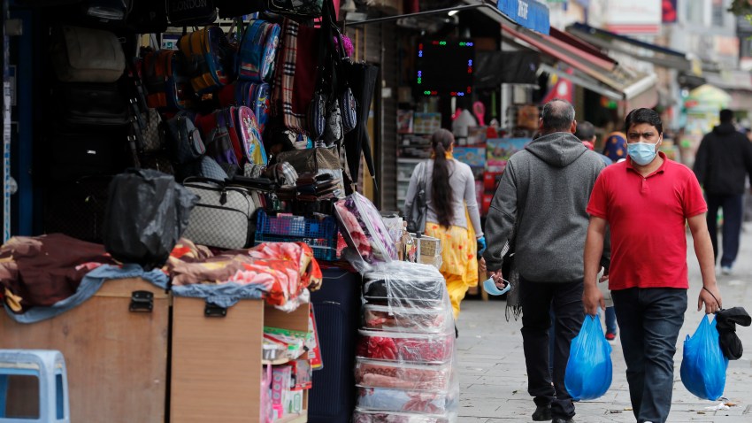 Shoppers walk past opened retail shops as coronavirus restrictions on non-essential retailers were lifted in London, Friday, June 19, 2020.