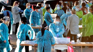 In this June 27, 2020, file photo, medical personnel prepare to test hundreds of people lined up in vehicles in Phoenix's western neighborhood of Maryvale.