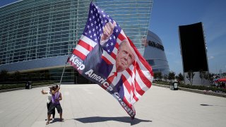 Two Trump supporters pose for photos with a giant Trump flag outside BOK Center, site of Trump's first political rally since the start of the coronavirus pandemic, June 18, 2020 in Tulsa, Okla.