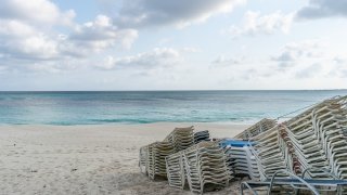 Lounge chairs sit stacked on a beach while temporarily closed in Nassau, Bahamas, on Friday, April 24, 2020. Local forecasters in the Bahamas said Arthur’s showers have lingered over the islands of Grand Bahama and Abaco, which are still struggling to recover after being hit by a Category 5 hurricane last year.