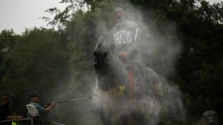 Workers clean graffiti from a statue of Belgium's King Leopold II in Brussels on Thursday, June 11, 2020, that was targeted by protesters during a Black Lives Matter demonstration.