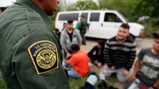In this Thursday, March 14, 2019, file photo, a Border Patrol agent talks with a group suspected of having entered the U.S. illegally near McAllen, Texas.