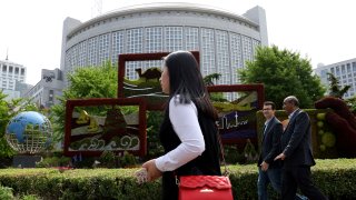 In this April 19, 2019, file photo, foreigners pass by the Chinese Foreign Ministry in Beijing, China.