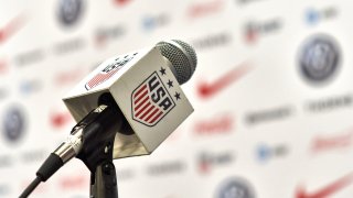 A detailed view of a press conference microphone is seen with the USA Soccer Federation logo.