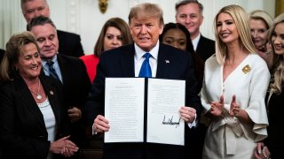 President Donald Trump, with Ivanka Trump, signs an executive order after delivering remarks at the White House Summit on Human Trafficking in the East Room at the White House on Friday, Jan. 31, 2020, in Washington.