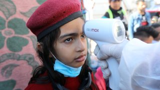 A girl receives a temperature test at Tahrir Square in Baghdad, Iraq