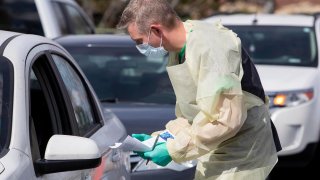 Nurse manager Cullen Anderson, RN, screens people in a line of cars waiting to be tested for COVID-19 at a drive-thru testing station at St. Luke's Meridian Medical Center Tuesday, March 17, 2020.