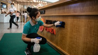 A staff wearing a face mask, amid concerns of the COVID-19 coronavirus, cleans the counter at a shopping center in Yangon on March 18, 2020.