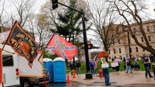 Demonstrators, waving a Confederate States flag (2nd L), take part in an "American Patriot Rally," organized on April 30, 2020, by Michigan United for Liberty on the steps of the Michigan State Capitol in Lansing, demanding the reopening of businesses.