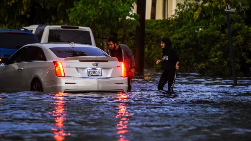 People walk in flooded water during a heavy rainfall in Miami, on May 26, 2020. – Residents of South Florida couldn’t enjoy the recent reopening of restaurants, businesses, and beaches after almost two months of quarantine due to the pandemic: three days in a row of heavy rains, which reached 6 inches on May 26, caused severe floods in Miami and other coastal cities affected by rising sea levels. (Photo by CHANDAN KHANNA / AFP) (Photo by CHANDAN KHANNA/AFP via Getty Images)