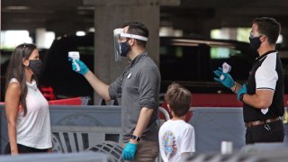 Visitors have their temperatures checked as they arrive at Universal Studios theme park on the first day of reopening after the shutdown during the coronavirus pandemic, on June 5, 2020, in Orlando, Florida. (Photo by Gregg Newton / AFP)