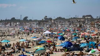 Large crowds gather near the Newport Beach Pier in Newport Beach on Saturday, April 25, 2020 to cool off during the hot weather despite the coronavirus pandemic.