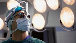 Surgeon wearing headlamp and surgery loupes