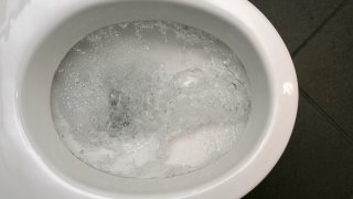 Water pours down a toilet.