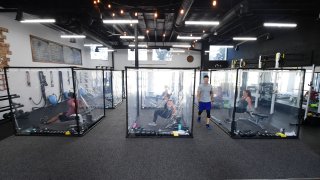 Peet Sapsin leads a class at Inspire South Bay Fitness with students behind plastic sheets in their workout pods while observing social distancing on June 15, 2020 in Redondo Beach, California, as the gym reopens under California's coronavirus Phase 3 reopening guidelines.