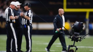 Referees confer as a malfunctioned SkyCam sits on the field, causing a stoppage the NFL wild-card playoff football game between the New Orleans Saints and the Minnesota Vikings