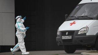 A medical worker wearing protective gear directs an ambulance at a hospital for coronavirus patients, April 27, 2020, in Kommunarka, outside Moscow, Russia.