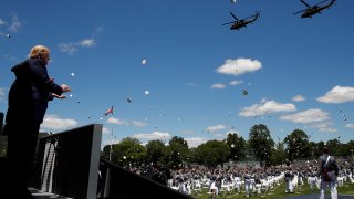 President Donald Trump applauds as Army helicopters fly over and West Point cadets toss their caps into the air at the end of commencement ceremonies on the parade field, at the United States Military Academy in West Point, N.Y., Saturday, June 13, 2020.