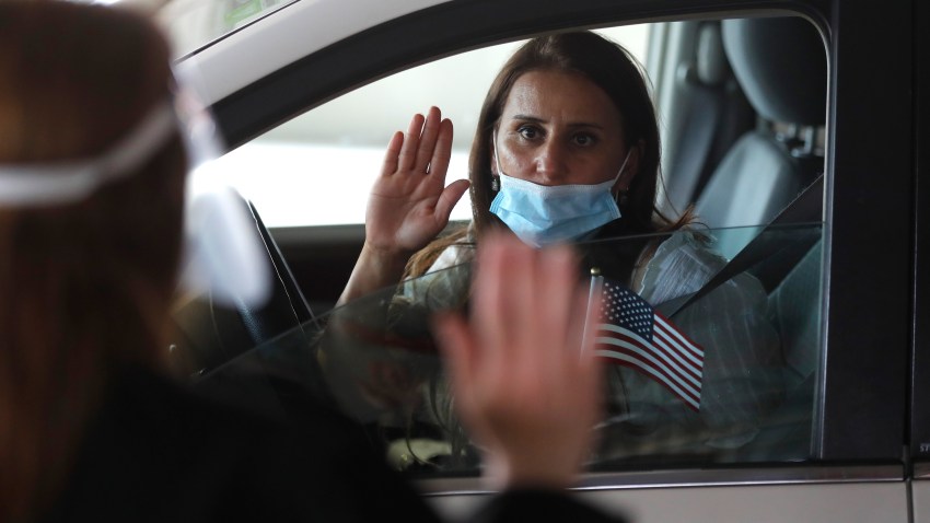 In this Friday, June 26, 2020 photo, U.S. District Judge Laurie Michelson, left, administers the Aath of Citizenship to Hala Baqtar during a drive-thru naturalization service in a parking structure at the U.S. Citizenship and Immigration Services headquarters on Detroit's east side. The ceremony is a way to continue working as the federal courthouse is shut down due to the coronavirus. The U.S. has resumed swearing in new citizens but the oath ceremonies aren't the same because of COVID-19 and a budget crisis at the citizenship agency threatens to stall them again.