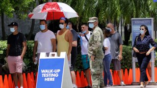 People wait in line at a walk-up testing site for COVID-19 during the new coronavirus pandemic, Tuesday, June 30, 2020, in Miami Beach, Fla.