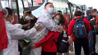 A medical worker from China's Jilin Province, in red, embraces a colleague at Wuhan Tianhe International Airport in central China's Hubei Province, Wednesday, April 8, 2020.