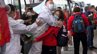 A medical worker from China's Jilin Province, in red, embraces a colleague at Wuhan Tianhe International Airport in central China's Hubei Province, Wednesday, April 8, 2020.