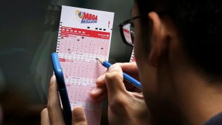 Customers fill out Mega Millions lottery tickets outside of a convenience store in Lower Manhattan, October 23, 2018 in New York City.