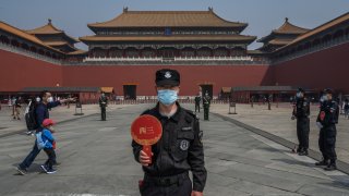In this May 1, 2020, file photo, a Chinese guard wears a protective mask as he stands at the entrance to the Forbidden City as it re-opened to limited visitors or the May holiday in Beijing, China.