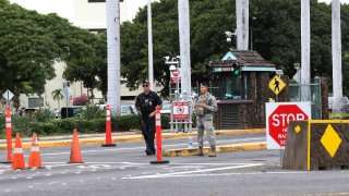 Security stand outside the main gate at Joint Base Pearl Harbor-Hickam, Wednesday, Dec. 4, 2019, in Hawaii. A shooting at Pearl Harbor naval shipyard in Hawaii left at least one person injured Wednesday, military and hospital officials said.
