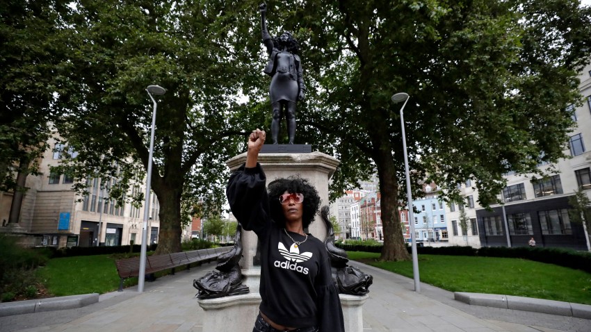 Jen Reid poses for photographs in front of the new black resin and steel statue portraying her, entitled "A Surge of Power (Jen Reid) 2020" by artist Marc Quinn after the statue was put up this morning on the empty plinth of the toppled statue of 17th century slave trader Edward Colston, which was pulled down during a Black Lives Matter protest in Bristol, England, Wednesday, July 15, 2020. On June 7 anti-racism demonstrators pulled the 18-foot (5.5 meter) bronze likeness of Colston down, dragged it to the nearby harbor and dumped it in the River Avon — sparking both delight and dismay in Britain and beyond.