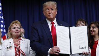 U.S. President Donald Trump holds an executive order on lowering drug prices after being signed during a ceremony in the Eisenhower Executive Office Building in Washington, D.C., U.S., on Friday, July 24, 2020. Trump announced new policies aimed at lowering prescription drug prices under Medicare by linking them to rates paid in other countries and allowing Americans to buy prescription medication imported from Canada.