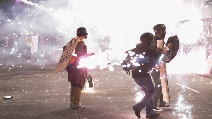 Protesters walk away from crowd control munitions launched by federal officers during a Black Lives Matter protest at the Mark O. Hatfield United States Courthouse Sunday, July 26, 2020, in Portland, Ore.