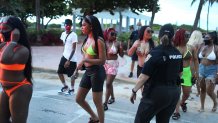 A Miami Beach police officer directs people out of the entertainment district as a curfew from 8pm to 6am is put in place on July 18, 2020 in Miami Beach, Florida. The City of Miami Beach put the curfew back into place to fight the spread of the coronavirus (COVID-19), which has spiked in recent days after the reopening of businesses.