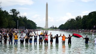 People pose for a photo in the Reflecting Pool in the shadow of the Washington Monument as they attend the March on Washington, Friday, Aug. 28, 2020, at the Lincoln Memorial in Washington, on the 57th anniversary of the Rev. Martin Luther King Jr.'s "I Have A Dream" speech.