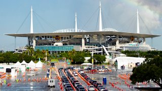 A rainbow arches overhead as vehicles line up at the COVID-19 drive-thru testing center at Hard Rock Stadium in Miami Gardens as the coronavirus pandemic continues on Sunday, July 19, 2020. (David Santiago/Miami Herald/Tribune News Service via Getty Images)