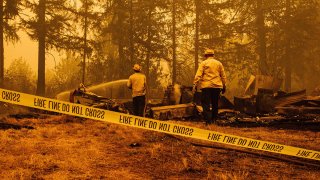 Oregon firefighters work behind caution tape in Mill City, Oregon, Sept. 10, 2020, as they battle the Santiam Fire.