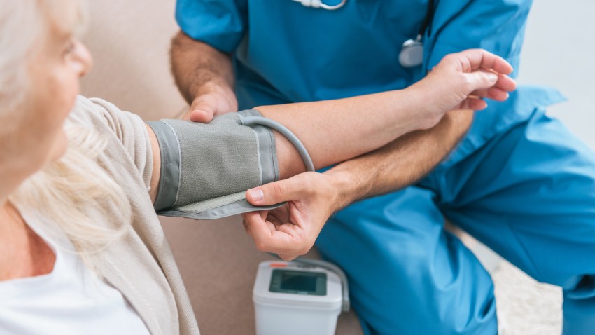 cropped shot of caregiver measuring blood pressure to senior woman