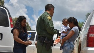 In this file photo, two young mothers from Honduras, L and R, and their respective children - a 12-year-old, blocked, and 1-year-old - are detained by United States Border Patrol after rafting across the Rio Grande on the U.S.-Mexico border on Monday, June 25, 2018, in Granjeno, TX.