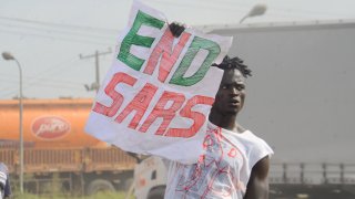 A protester holds a sign reading "End SARS"