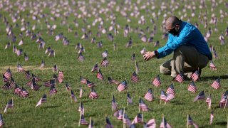 WASHINGTON, DC - SEPTEMBER 22: Chris Duncan, whose 75 year old mother Constance died from COVID on her birthday, photographs a COVID Memorial Project installation of 20,000 American flags on the National Mall as the United States crosses the 200,000 lives lost in the COVID-19 pandemic September 22, 2020 in Washington, DC. The flags are displayed on the grounds of the Washington Monument facing the White House.