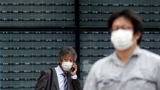 A man stands in front of a blank electronic stock board supposedly showing Japan's Nikkei 225 index at a securities firm in Tokyo Thursday, Oct. 1, 2020. Trading on the Tokyo Stock Exchange was suspended Thursday because of a problem in the system for relaying market information. Most other Asian markets were closed for national holidays.